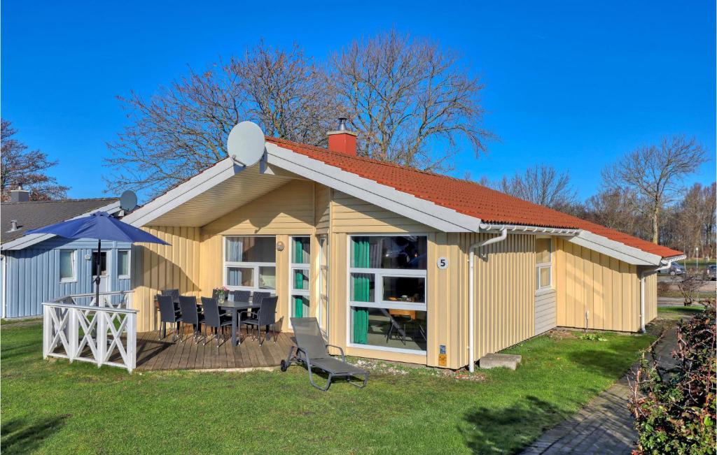 ein kleines gelbes Haus mit einem Tisch und Stühlen in der Unterkunft Strandblick 5 in Schönhagen