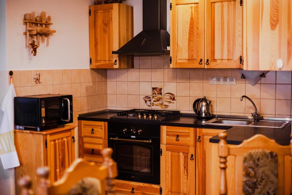 una cocina con armarios de madera y estufa negra en Gazdov dvor en Vavrišovo