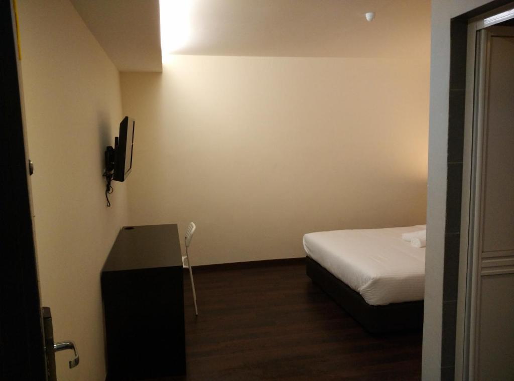 Habitación pequeña con cama y TV. en Dream Garden Hotel, en Klang