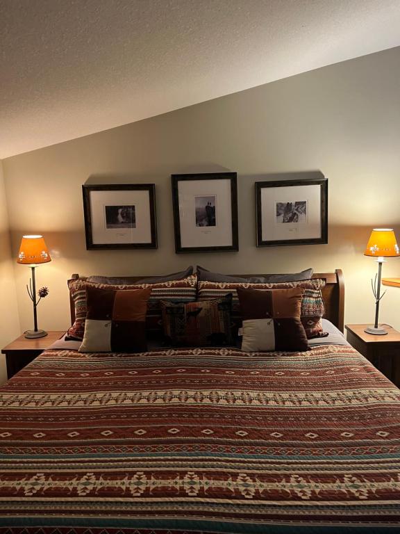 una camera con un grande letto con tre immagini appese al muro di Canmore Crossing a Canmore