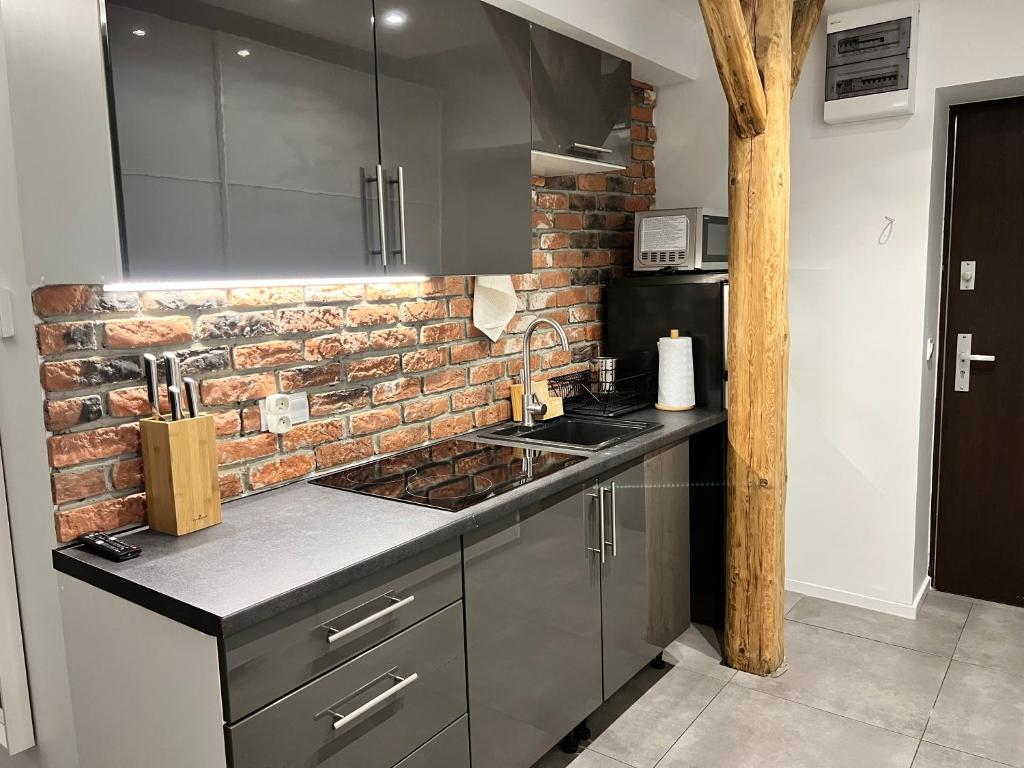 a kitchen with a brick wall and stainless steel appliances at Apartament Bronowice in Krakow