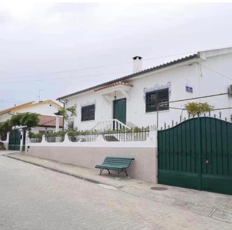 a green bench sitting in front of a white house at Casa de Azzancha in Azinhaga