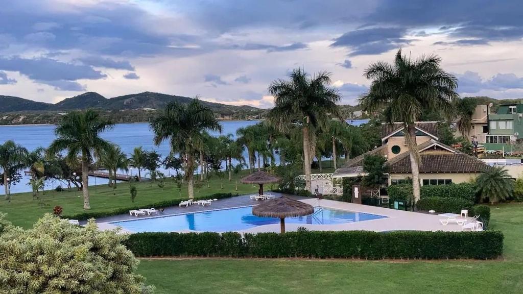 uma grande piscina com palmeiras e um lago em Completo apartamento em Resort na beira da lagoa em Florianópolis