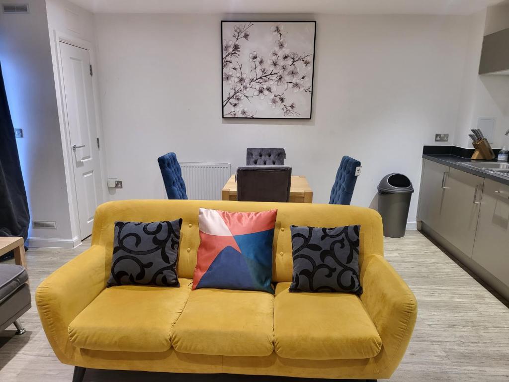 a yellow couch with pillows in a living room at Garland Apartment, Greenhithe 3 in Dartford