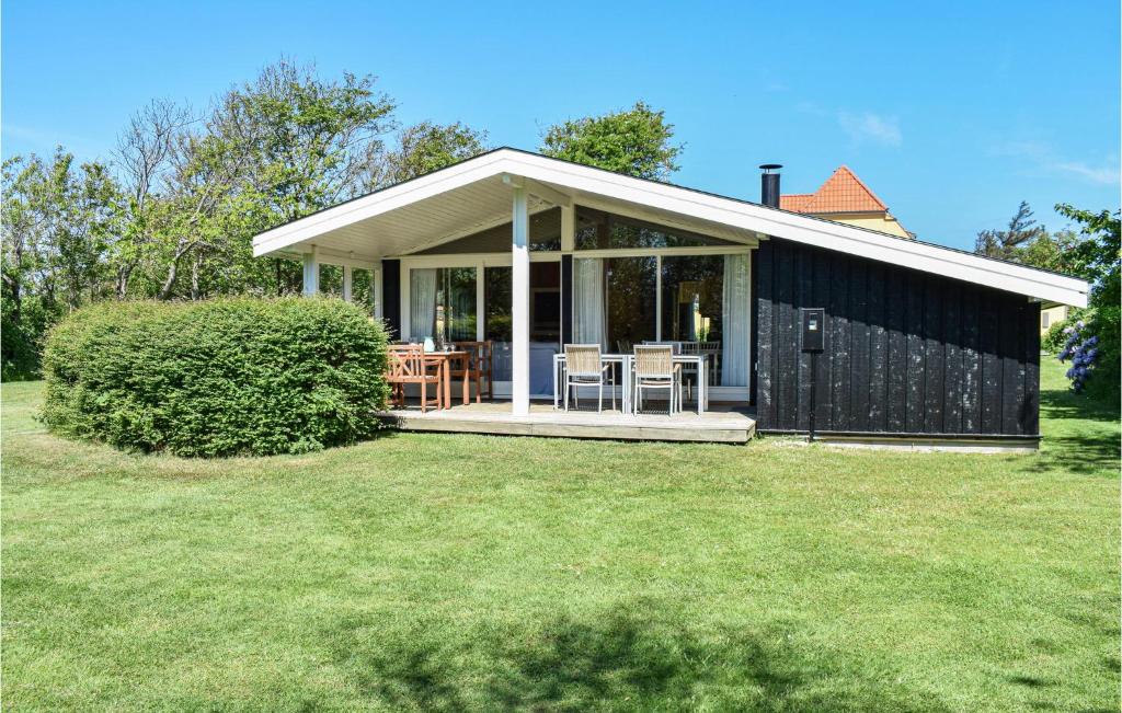 ein schwarzes Haus mit einer Veranda und Stühlen auf einem Rasen in der Unterkunft Cozy Home In Tisvildeleje With Wifi in Tisvildeleje