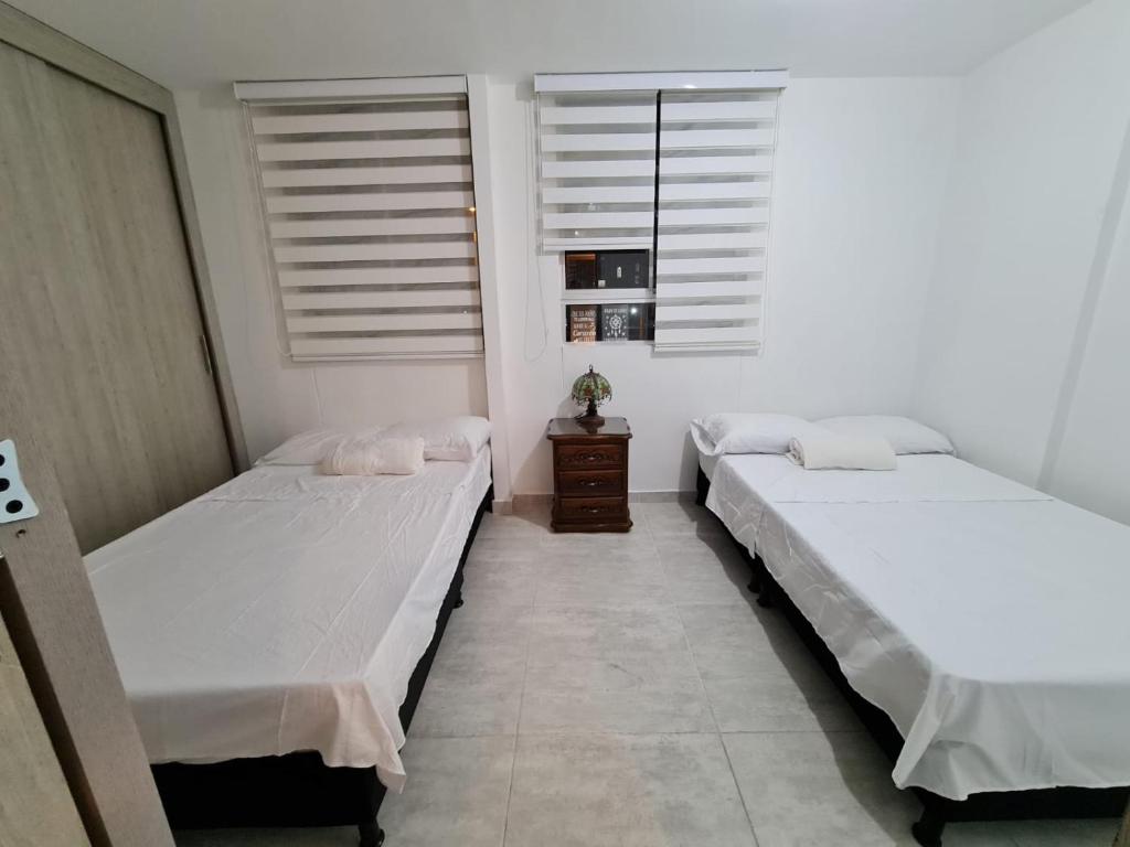 2 łóżka w pokoju z białymi ścianami i oknami w obiekcie APARTAMENTO SECTOR CONDINA cerca estadio-ukumari-consota-expofuturo w mieście Pereira