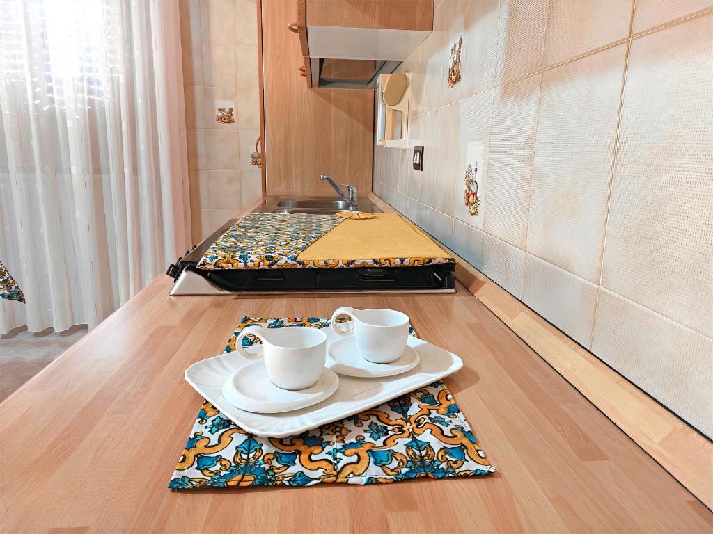 eine Küche mit zwei Tassen und einem Tablett auf dem Boden in der Unterkunft Casetta Orchidea A pochi passi dal Centro in Lampedusa