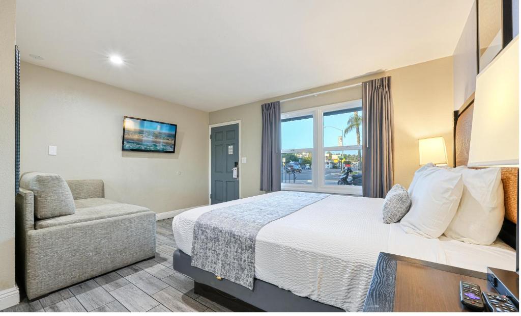 a bedroom with a bed and a chair and a window at Hotel Point Loma in San Diego