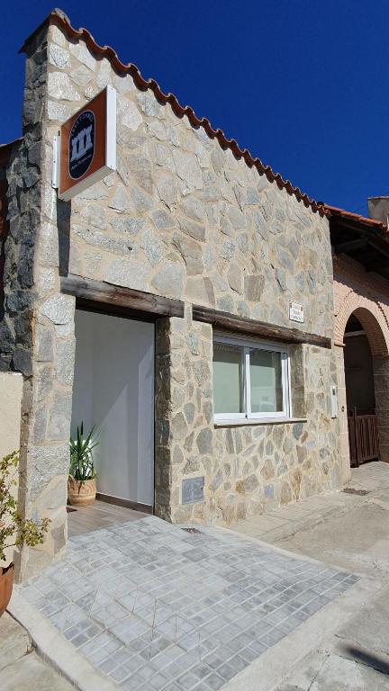 un edificio de piedra con un garaje y un cartel en él en Tres Torres Apartamento Turístico, en Almoharín