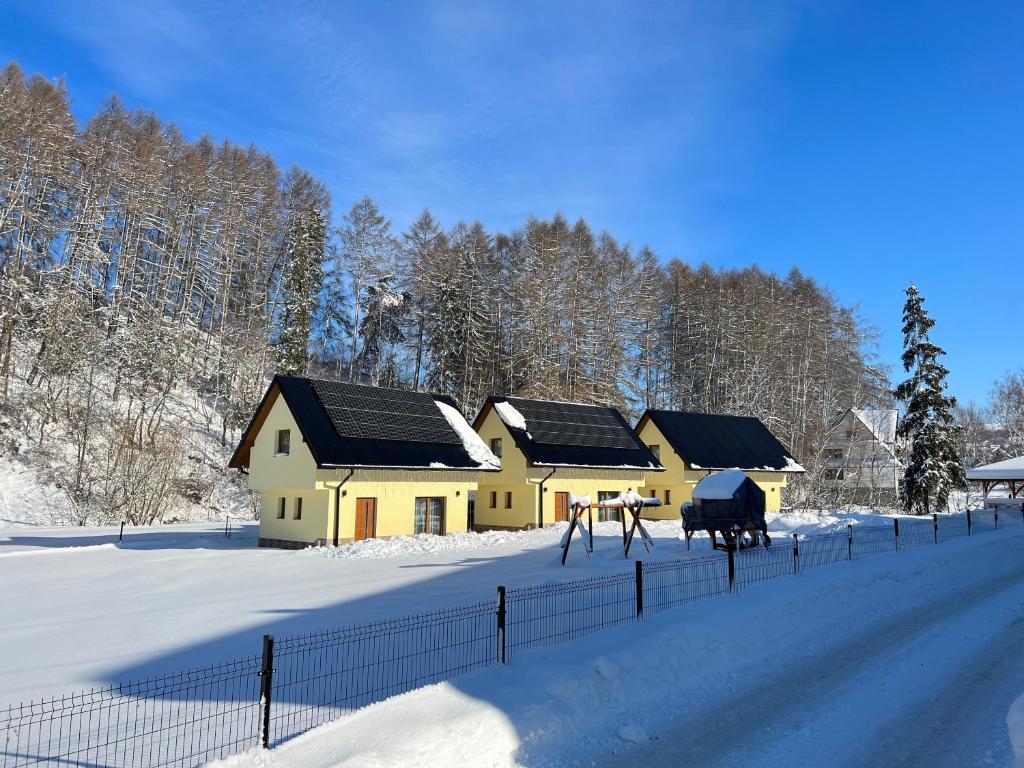 una casa en la nieve junto a una valla en Domki pod Grapą, en Trybsz