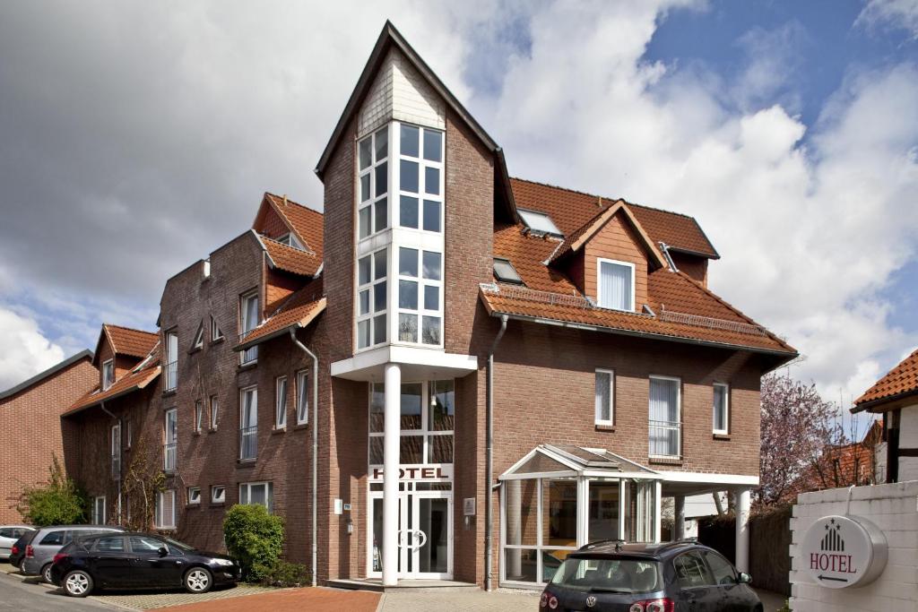ein großes Backsteingebäude mit spitzem Dach in der Unterkunft Hotel Am Braunen Hirsch in Celle