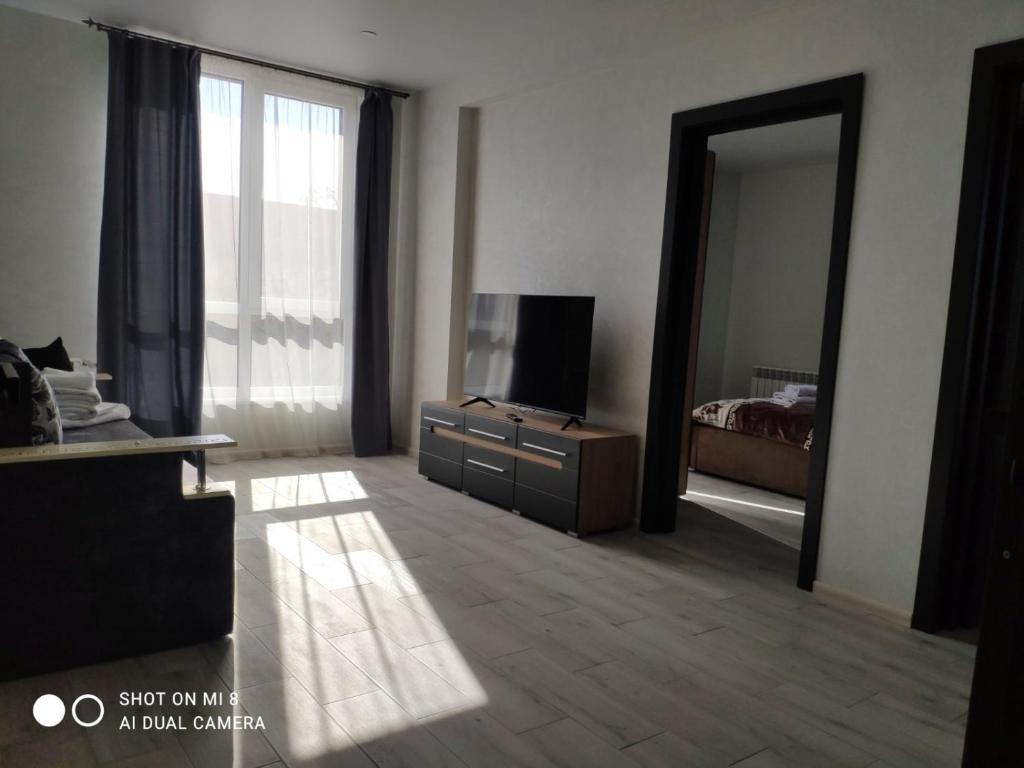 uma sala de estar com uma televisão, uma cama e um espelho em Apartmets Domovik Вместительная трьохкомнатная квартира em Mukacheve