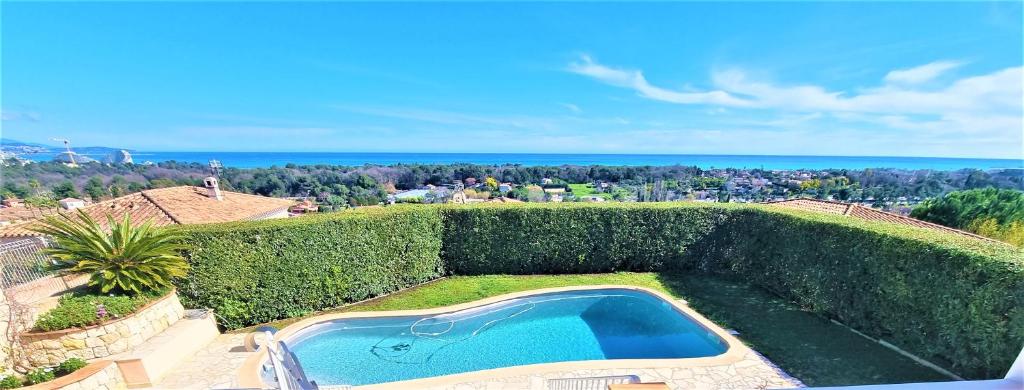een uitzicht over het zwembad in de tuin bij Villa piscine avec magnifique vue mer panoramique in Biot