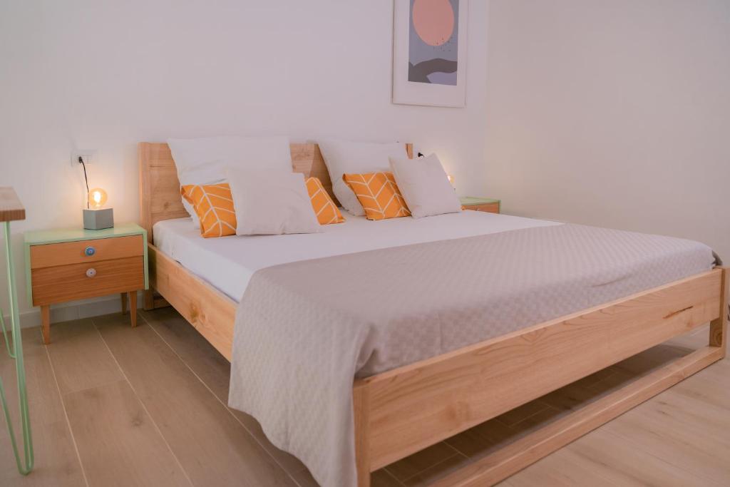 um quarto com uma cama de madeira com almofadas laranja e branca em Tiny house in the historic centre of Soverato em Soverato Superiore