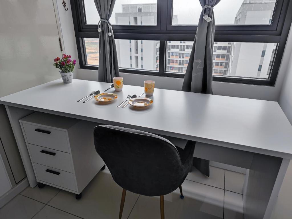 a white desk with a chair and two plates of food at Swiss Home Horizon Suite 1 in Sepang
