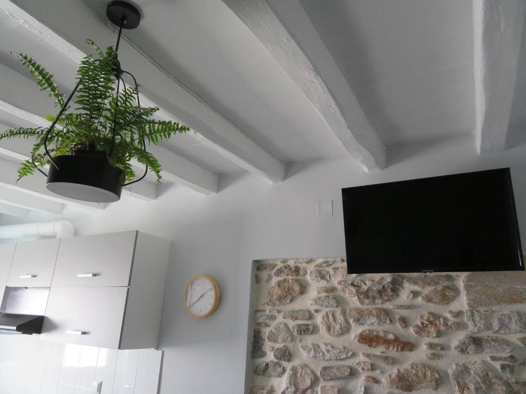 a living room with a tv and a stone wall at CASA SYRA in Ermoupoli
