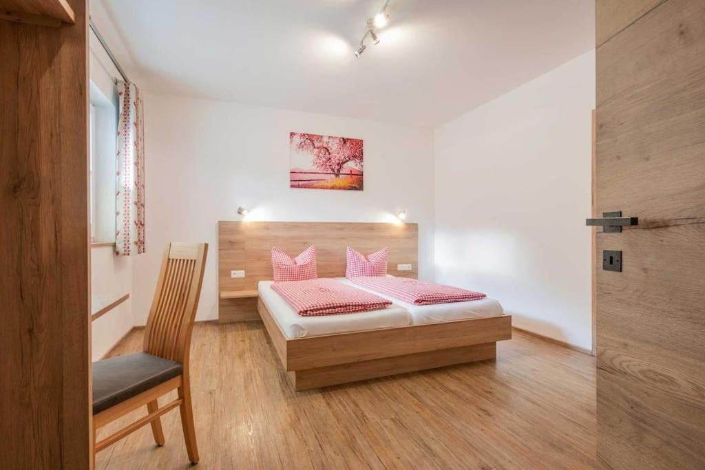 a bedroom with a bed with pink pillows and a chair at Haus Jedeler in Neustift im Stubaital