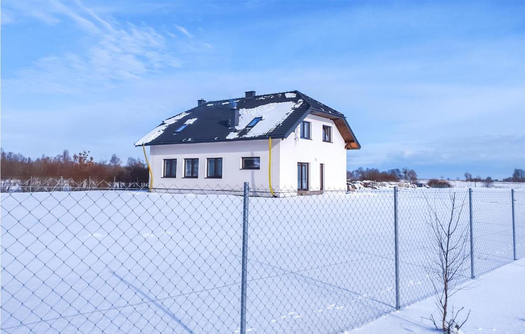 ein Haus hinter einem Zaun mit einem schneebedeckten Dach in der Unterkunft Stunning Home In Smoldzinski Las With Wifi in Smołdziński Las