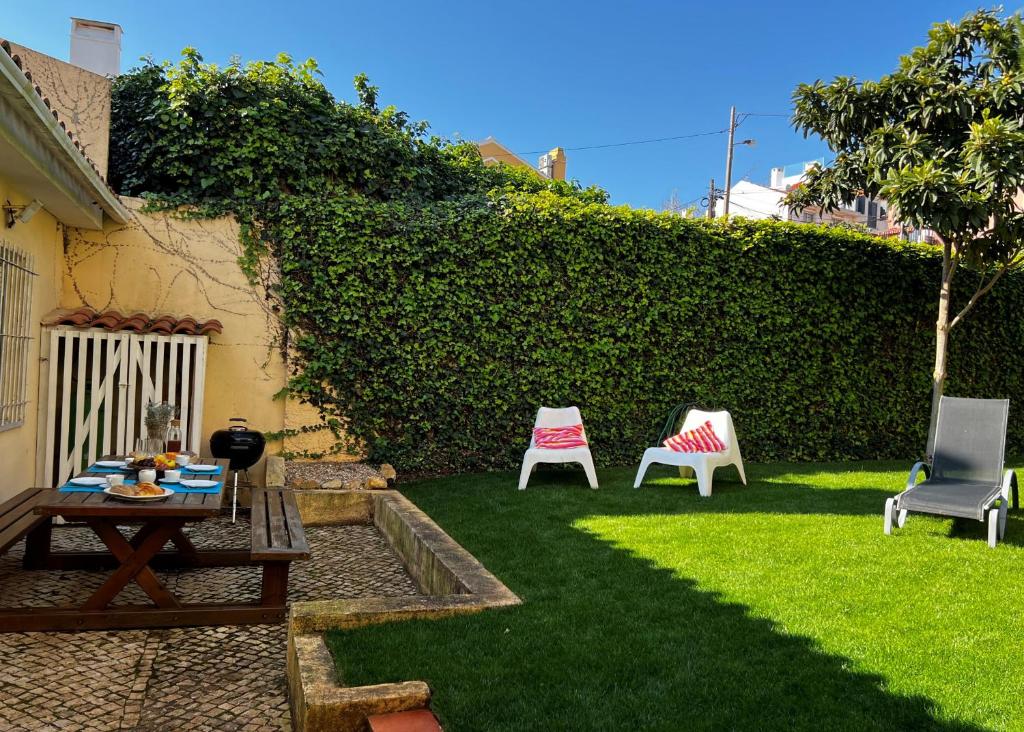 a backyard with a table and chairs and a hedge at Cascais center House with garden in Cascais