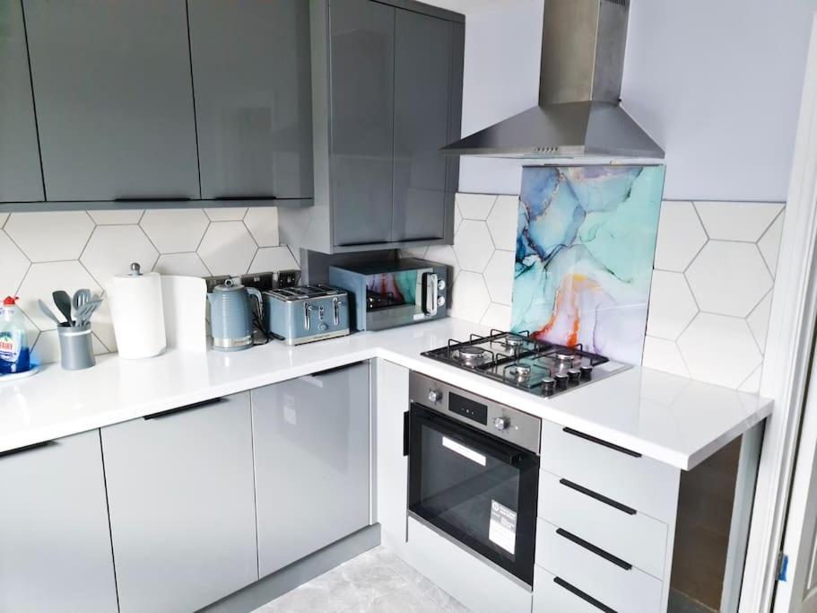 a kitchen with white cabinets and a stove top oven at The Navarone Blue Orchid Flat in London