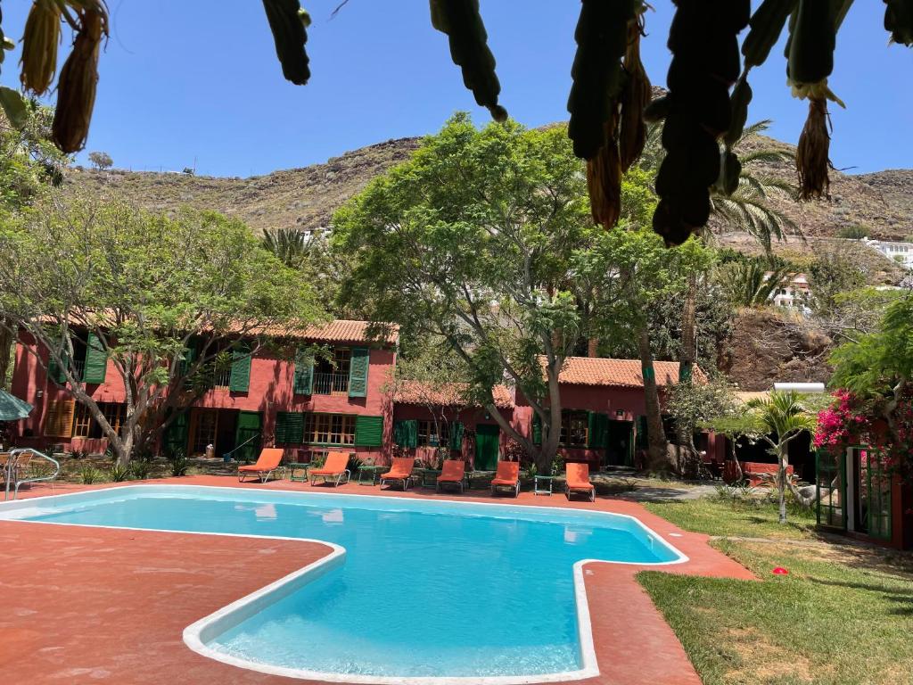 una piscina frente a un complejo con sillas y árboles en La Casa del Molino de Viento en Agaete