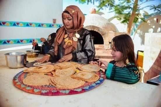 two young girls sitting at a table with a pizza at تحتمسنا كا بيت تحتمس house of tohotms in Nag` el-Qabba