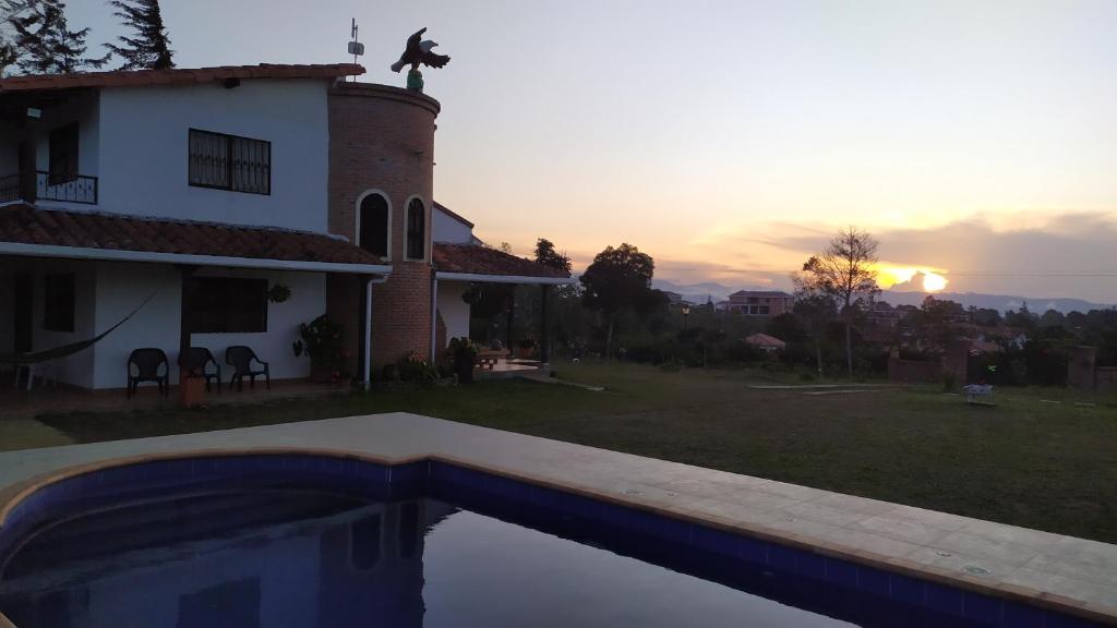 a house with a swimming pool in front of a sunset at Casa de Campo EL LAGUITO - Mesa de los Santos in Los Santos