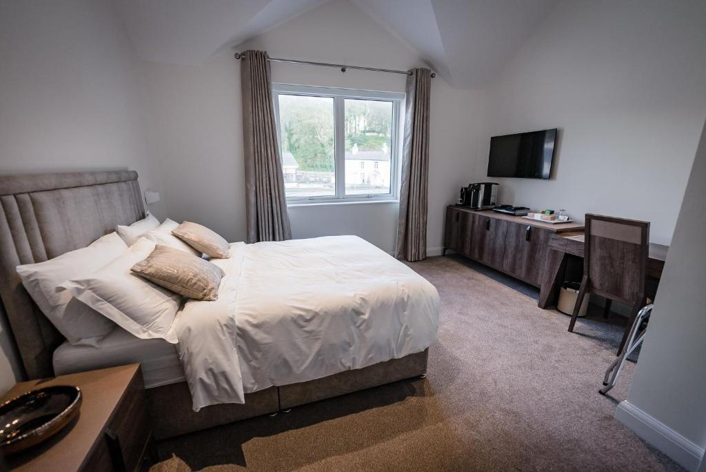 a bedroom with a bed and a desk and a window at Shore Hotel Laxey in Laxey