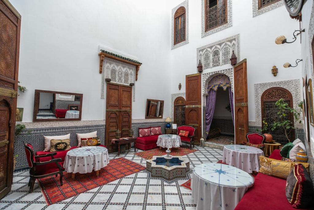 una sala de estar con mesas y sillas en un edificio en Riad Arabella en Fez