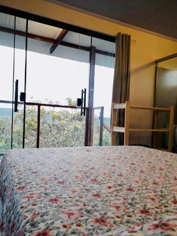 a bedroom with a bed and a large window at Chales Estrela Veadeiros in Alto Paraíso de Goiás