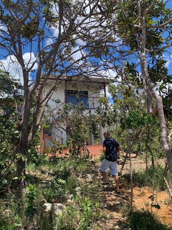 a man standing in front of a house behind trees at Chales Estrela Veadeiros in Alto Paraíso de Goiás