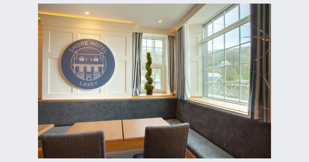 a dining room with a table and some windows at Shore Hotel Laxey in Laxey