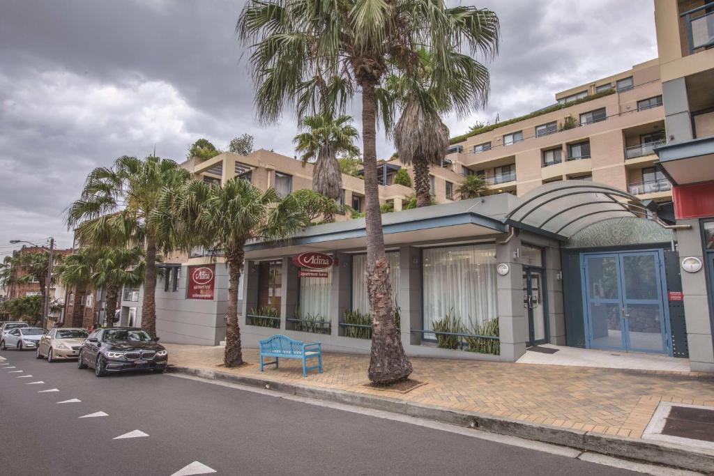 a building with palm trees on the side of a street at Adina Apartment Hotel Coogee Sydney in Sydney