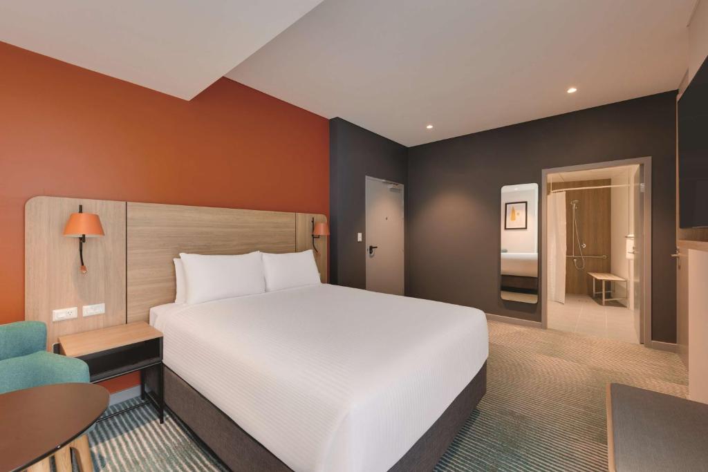 a bedroom with a large white bed and a desk at Travelodge Hotel Hurstville Sydney in Sydney