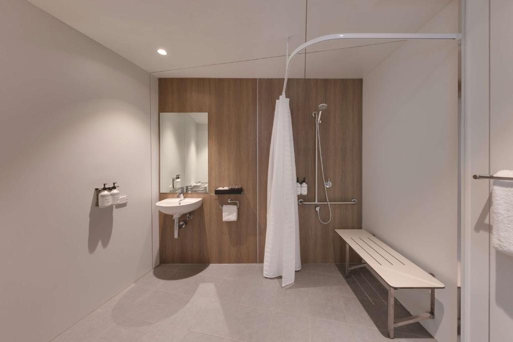 a bathroom with a sink and a shower with a bench at Travelodge Hotel Hurstville Sydney in Sydney