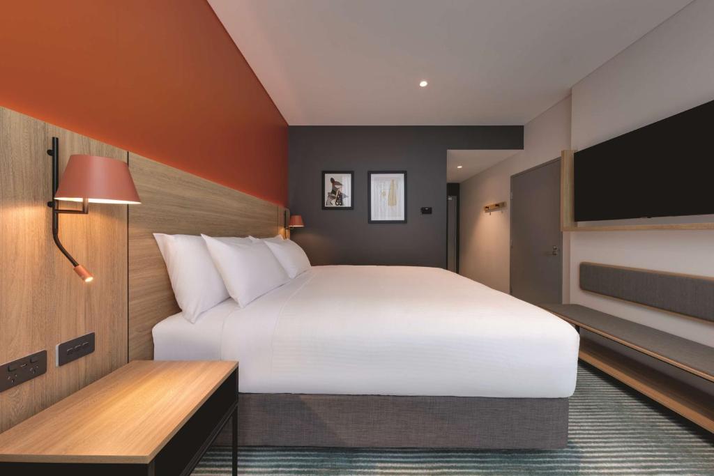 a bedroom with a large white bed and a flat screen tv at Travelodge Hotel Hurstville Sydney in Sydney