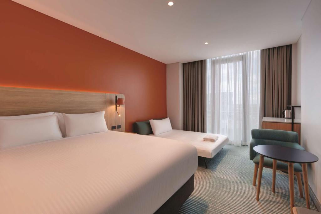 a hotel room with a large bed and a chair at Travelodge Hotel Hurstville Sydney in Sydney