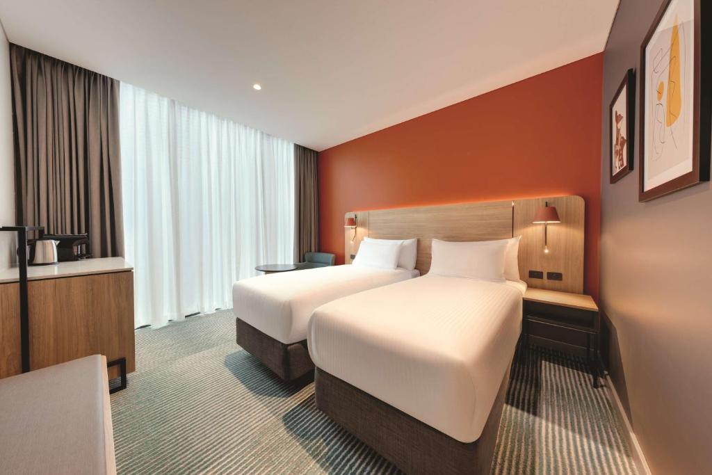 a hotel room with two beds and a desk at Travelodge Hotel Hurstville Sydney in Sydney