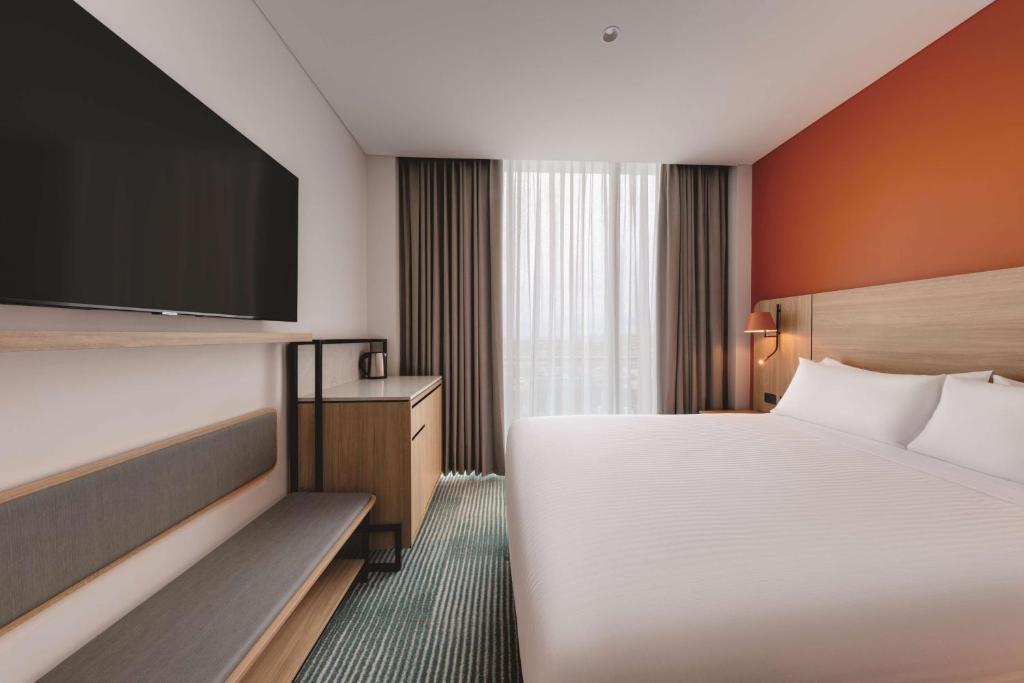 a hotel room with a bed and a flat screen tv at Travelodge Hotel Hurstville Sydney in Sydney