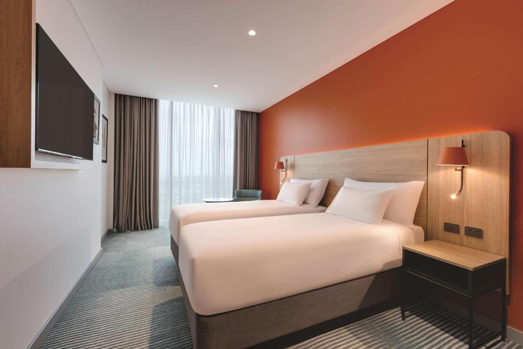 a hotel room with a large bed and a television at Travelodge Hotel Hurstville Sydney in Sydney