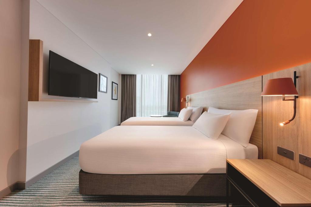 a hotel room with two beds and a flat screen tv at Travelodge Hotel Hurstville Sydney in Sydney