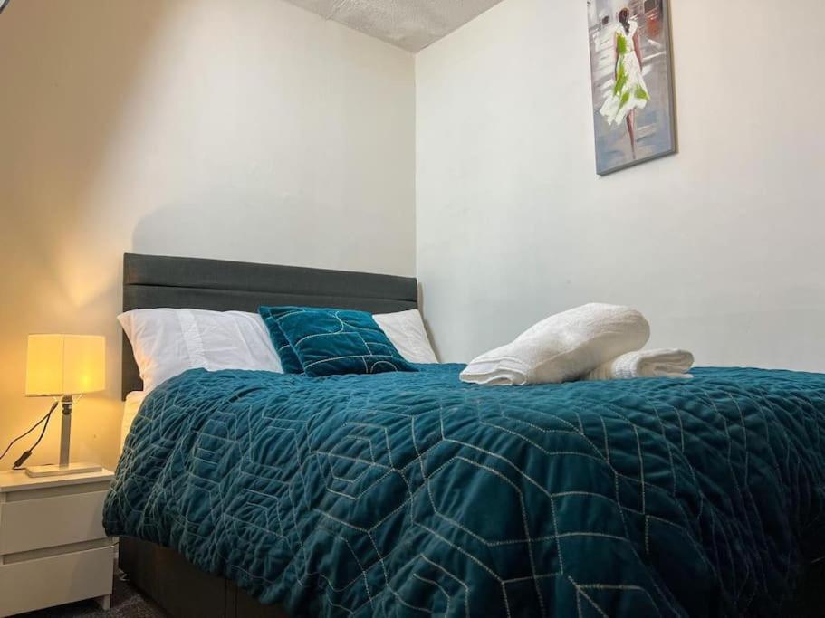 ein Bett mit blauer Decke in einem Schlafzimmer in der Unterkunft Adorable 2 bed house ideal for Family of Four in Manchester