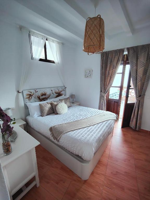 Un dormitorio con una gran cama blanca y una mesa en Las Lajas, Casa Rural, en Montejaque