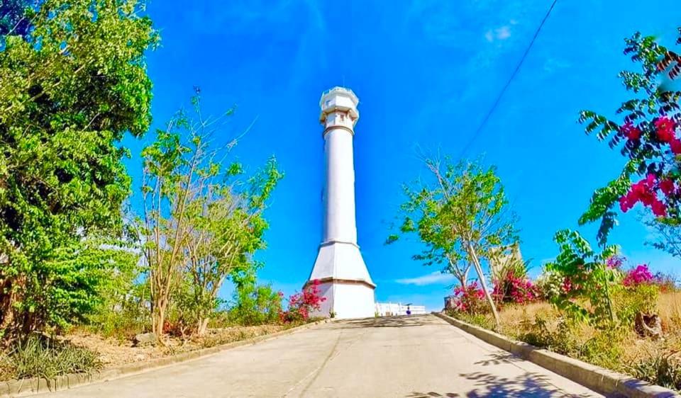 a lighthouse on the side of a road at Jeremias Transient Patar Bolinao near WhiteBeach LightHouse in Bolinao