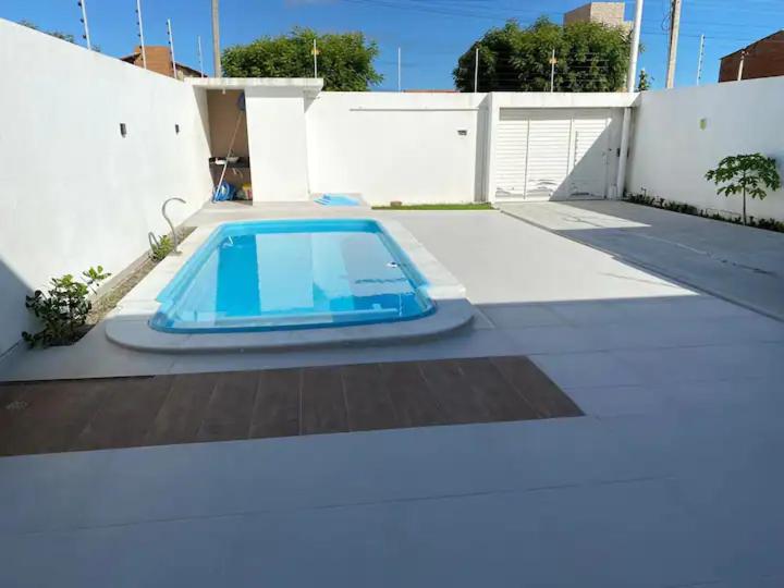 una piscina azul en un patio junto a una valla en CASA K en Barra de São Miguel