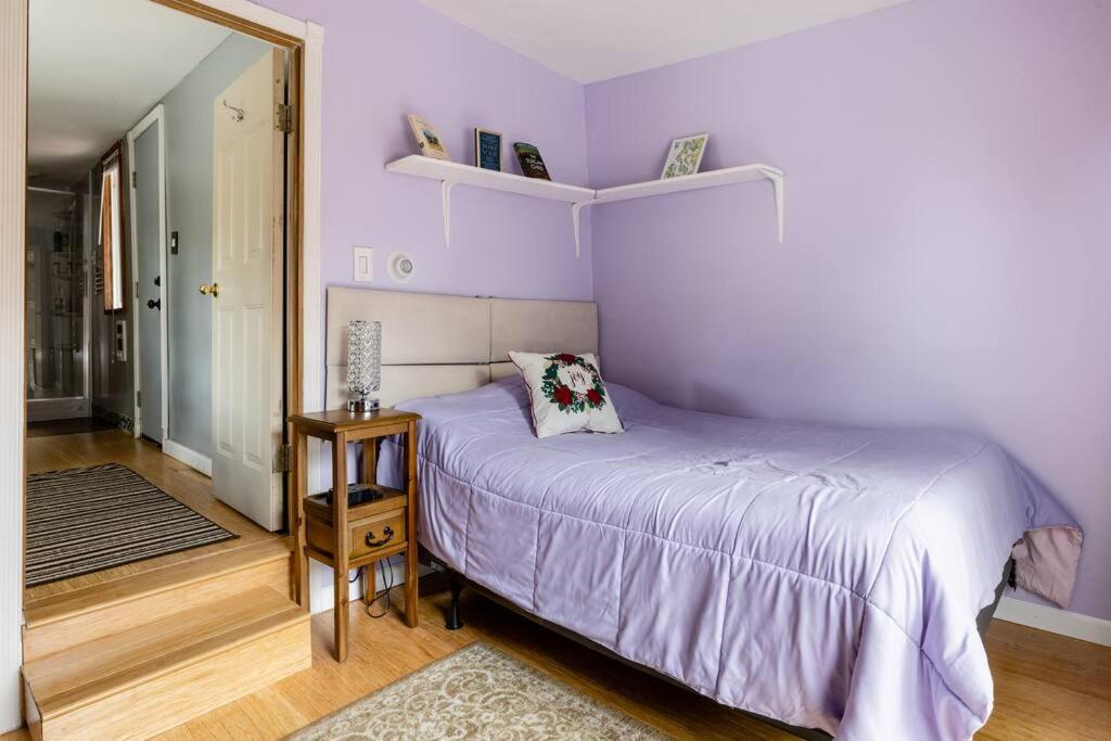 Dormitorio púrpura con cama y espejo en Tiny House with private Hot Tub near Seattle en Shoreline