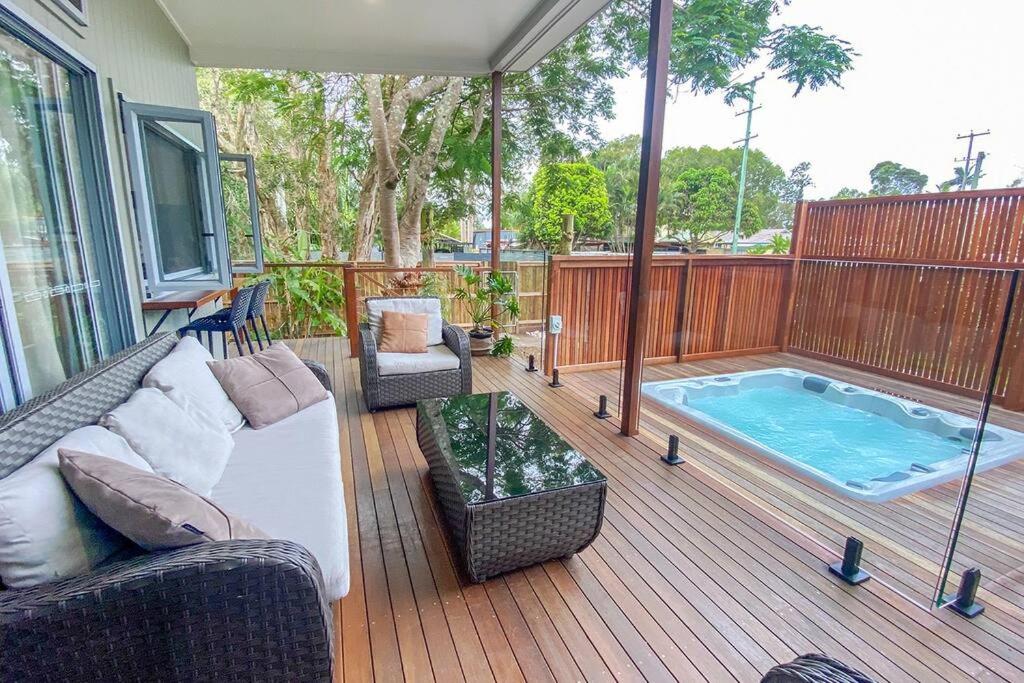 a patio with a couch and a swimming pool at Beach House with spa among the trees Coolum Beach in Coolum Beach