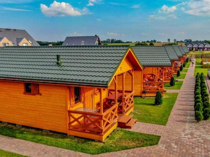 une grande maison en bois avec un toit noir dans l'établissement Cozy holiday houses near the sea, Sarbinowo, à Sarbinowo