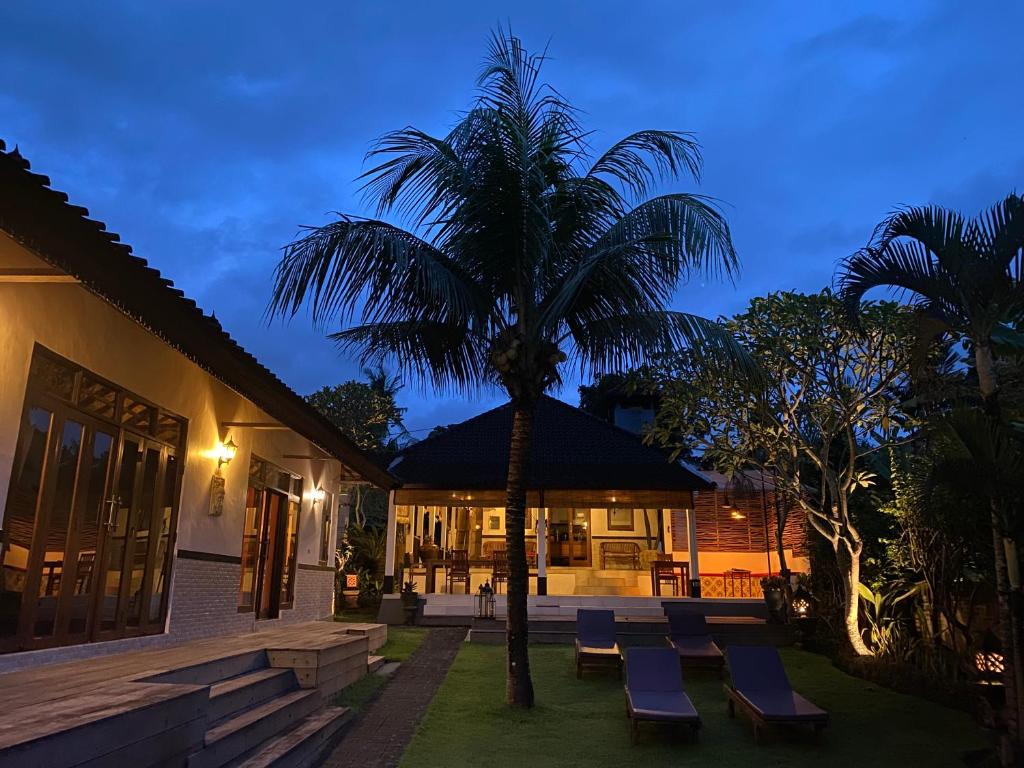 a resort with chairs and a palm tree at night at Agung Village in Tanah Lot