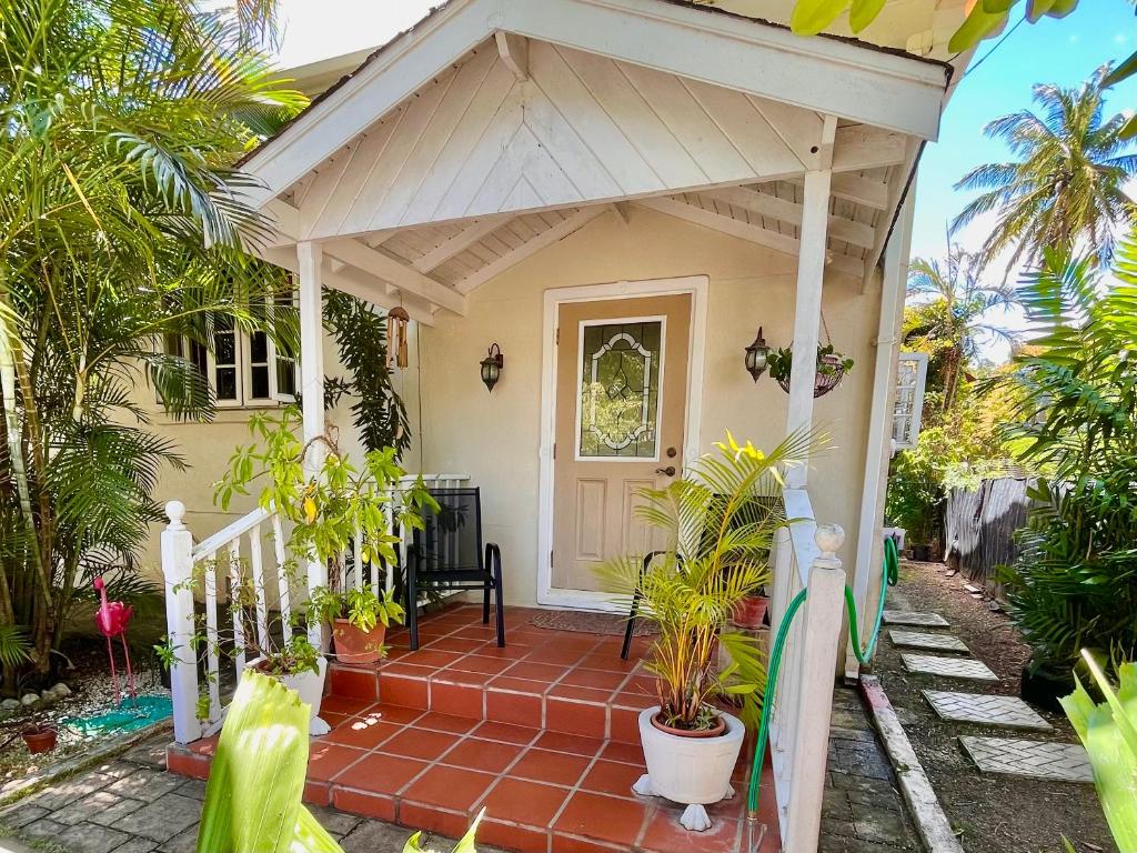 a small house with a porch with potted plants at Cozy 1 bedroom cottage w/pool in Bridgetown